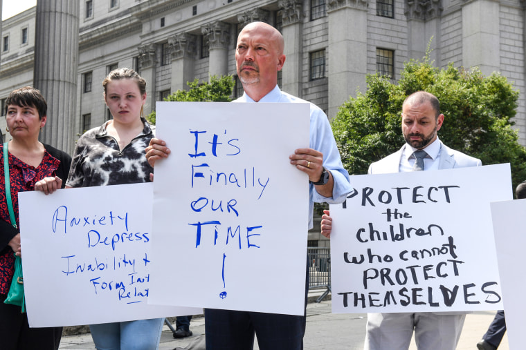 Patrick Noaker, center, holds a sign that says "It's finally our time" and to his left, someone holds a sign saying "Protect the children who cannot protect themselves"