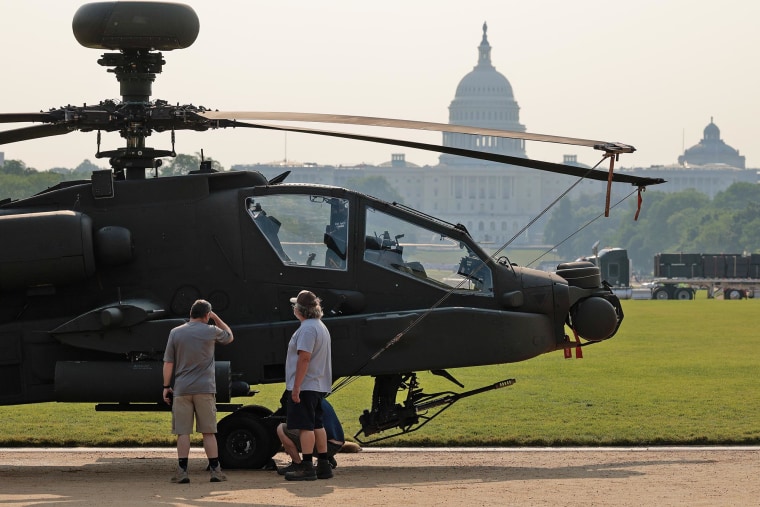 People pause to look at a U.S. Army AH-64 Apache attack helicopter parked on display on the National Mall on June 11, 2025.