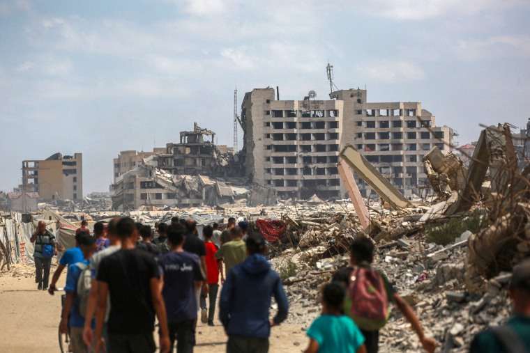 Palestinians walk on a dirt road.