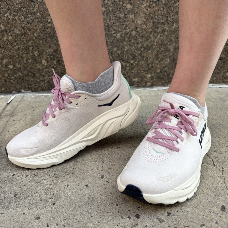A woman wearing a lavender pair of Hoka Arahi 8 sneakers.